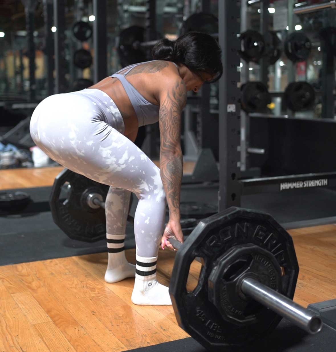 Coach in a gym, lifting a barbell loaded with weights.